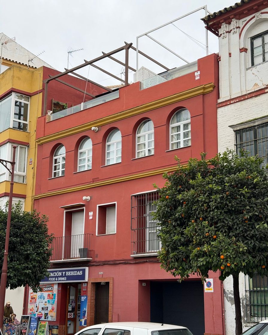 Aparcamiento en superficie en la periferia de Sevilla, con plazas marcadas vacías y árboles jóvenes