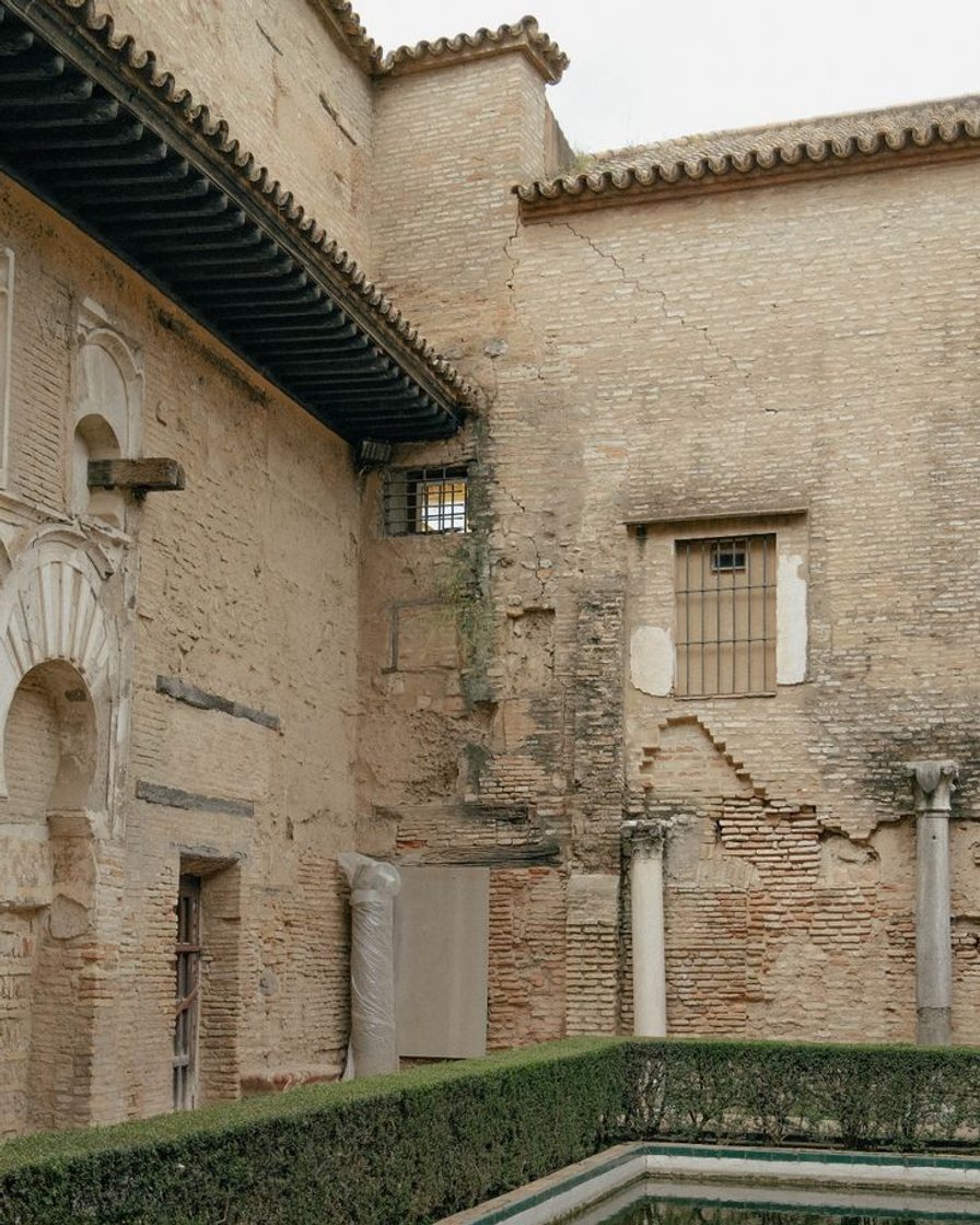 Parque de setos recortados y bancos de azulejos con una columnata curva al fondo, en Sevilla