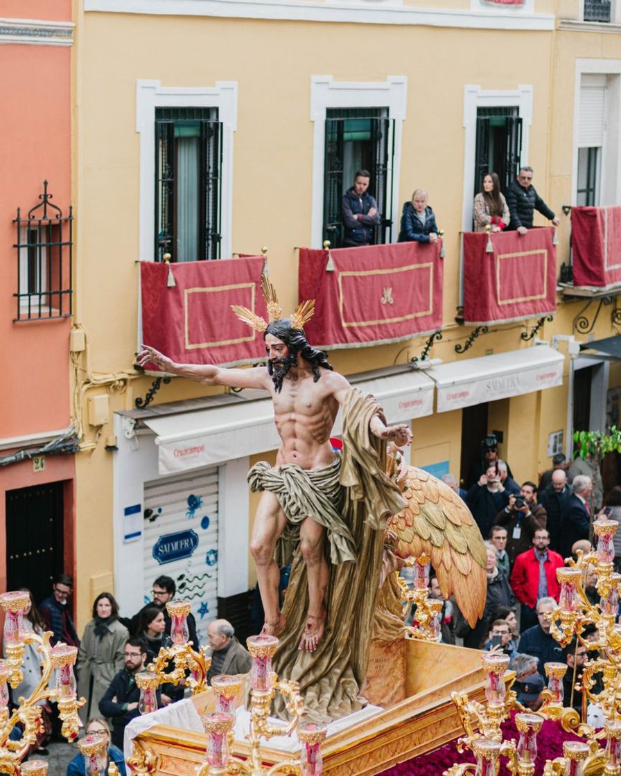 Paso de misterio pasando muy pegado a los balcones de una calle estrecha de Sevilla en su recorrido de vuelta, con vecinos asomados y el capataz de espaldas