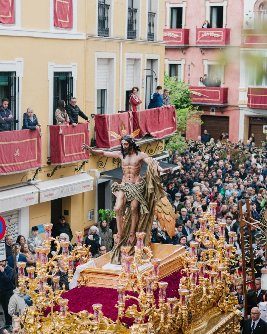 Paso de palio avanzando de noche por la calle Sierpes de Sevilla, con los balcones llenos y nazarenos de capirote en primer plano